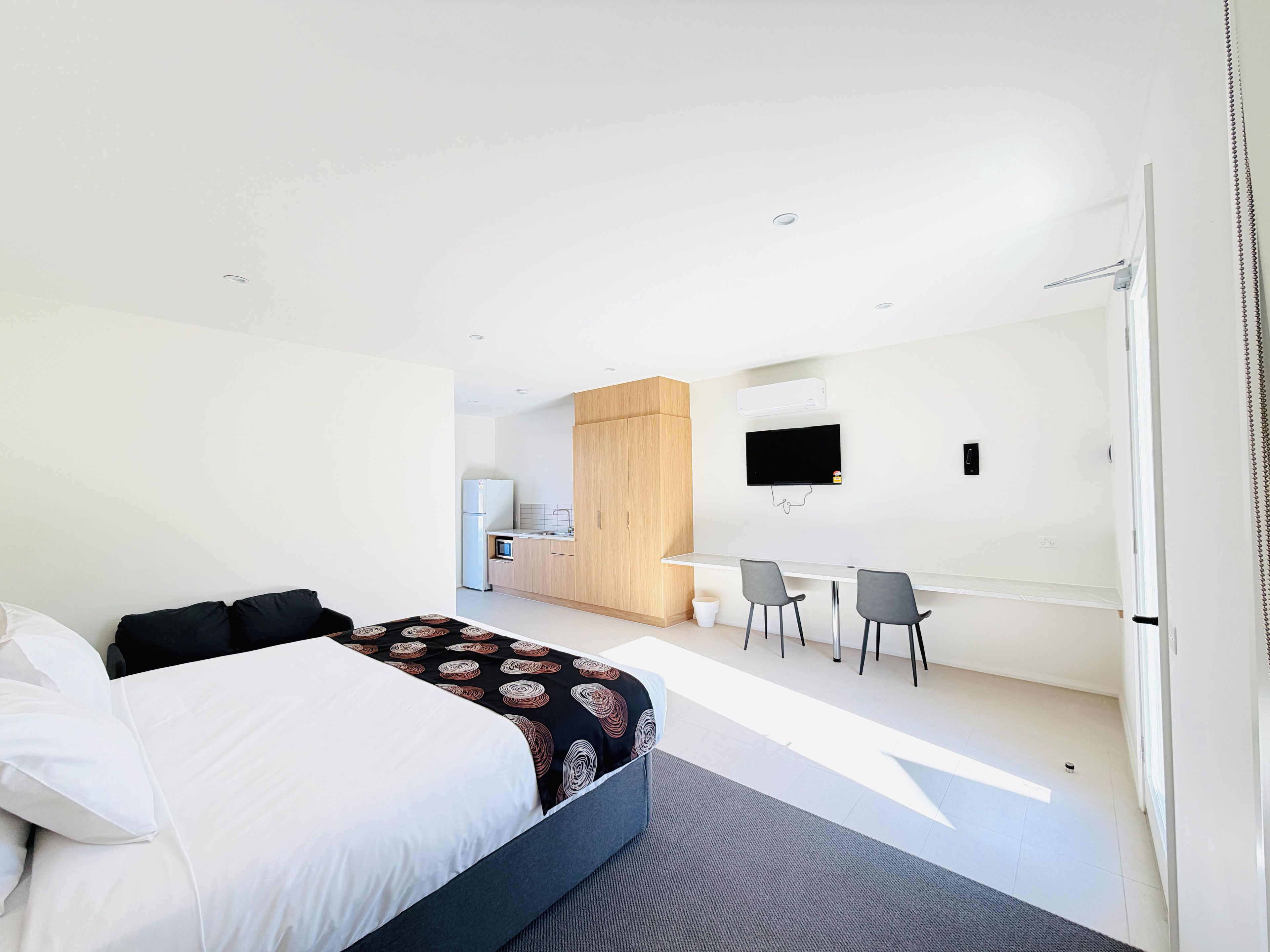 Une chambre d’hôtel moderne équipée d’un lit, d’un bureau et d’une télévision.