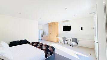 Une chambre d’hôtel moderne équipée d’un lit, d’un bureau et d’une télévision.