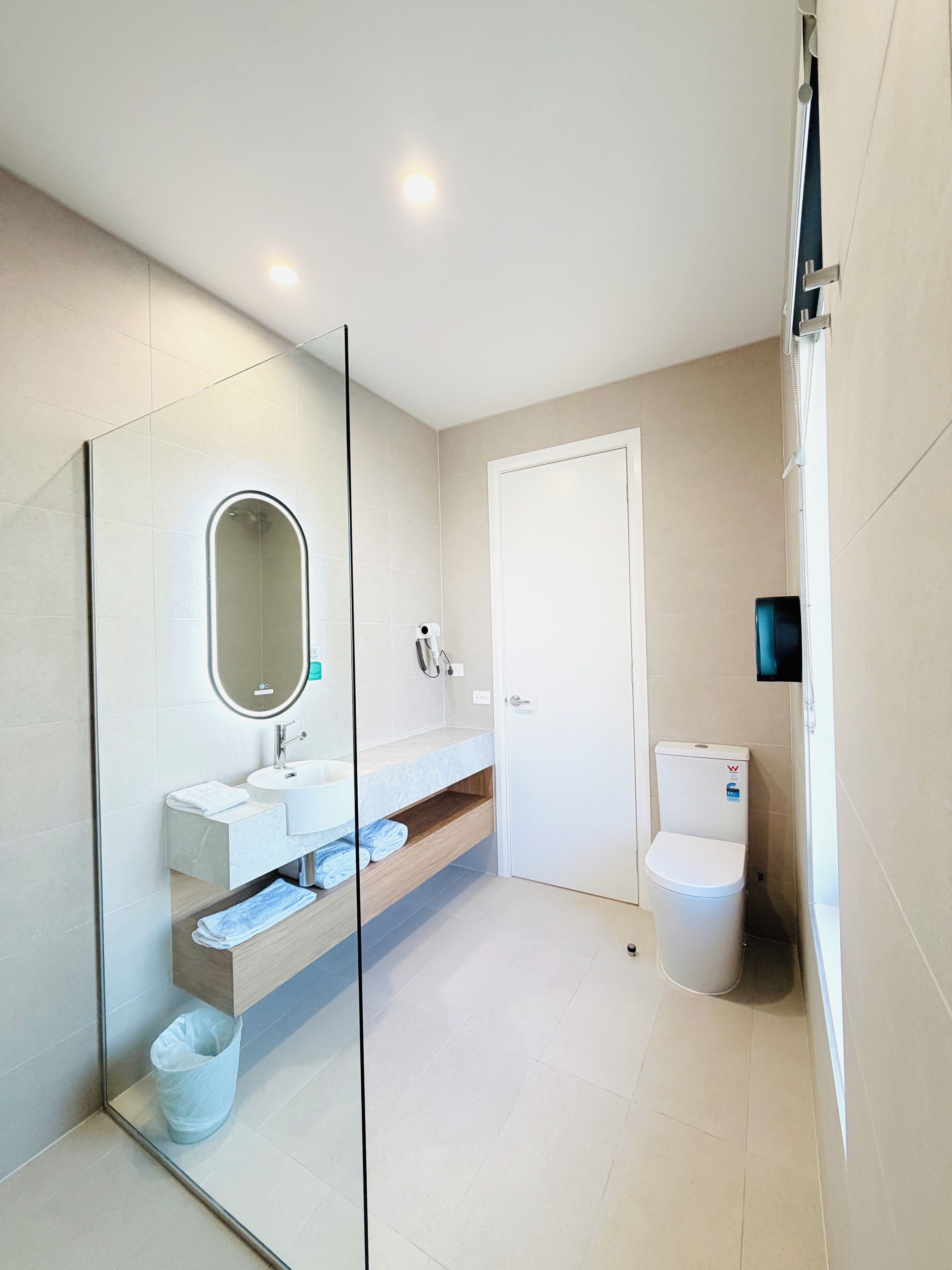 Un baño moderno con cabina de ducha de vidrio, lavabo blanco con encimera de mármol y retrete.