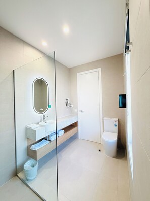 A modern bathroom with a glass-enclosed shower, a white sink with a marble countertop, and a toilet.