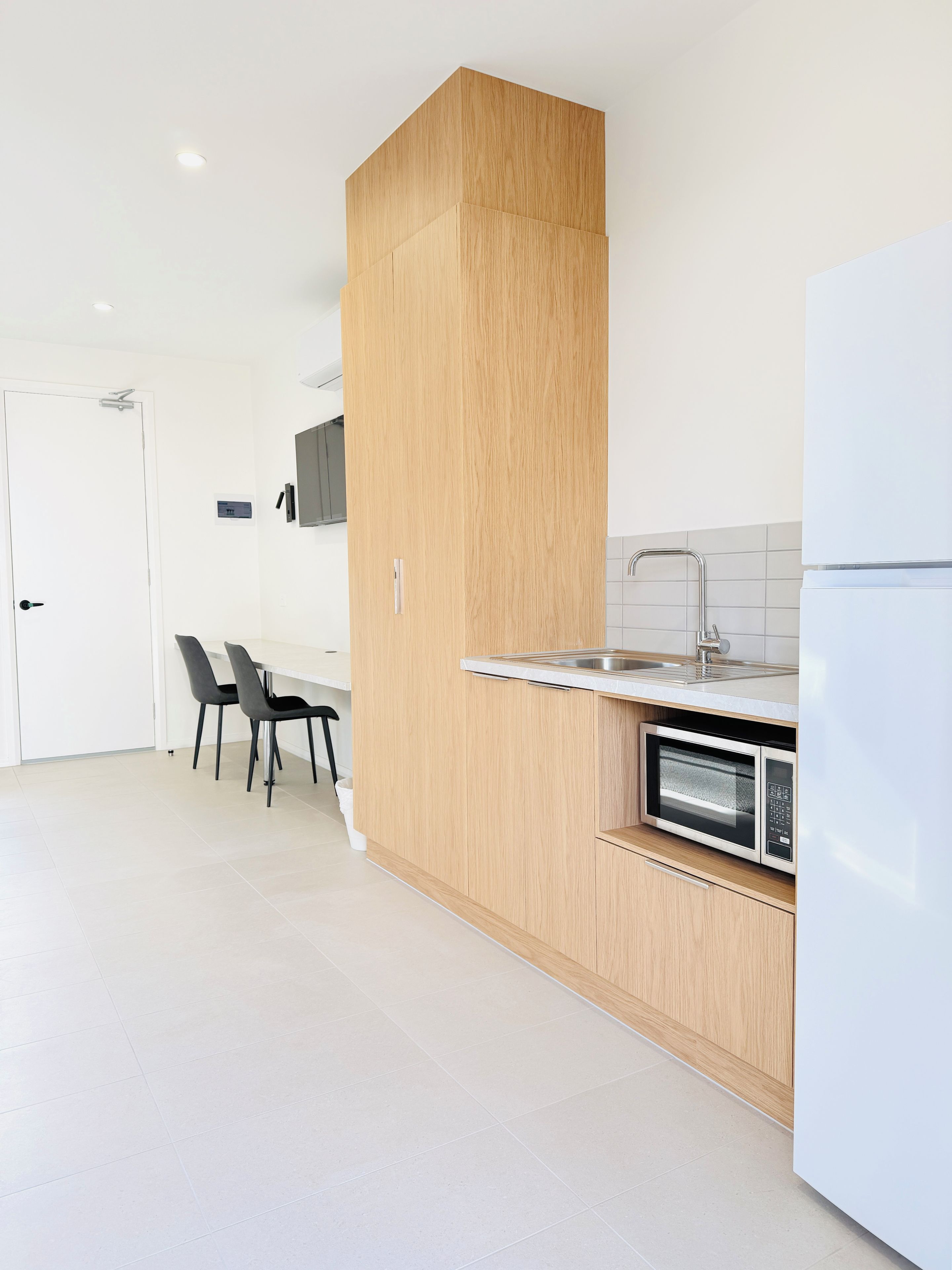 A modern kitchen with a built-in microwave, a sink, and a dining area with chairs.