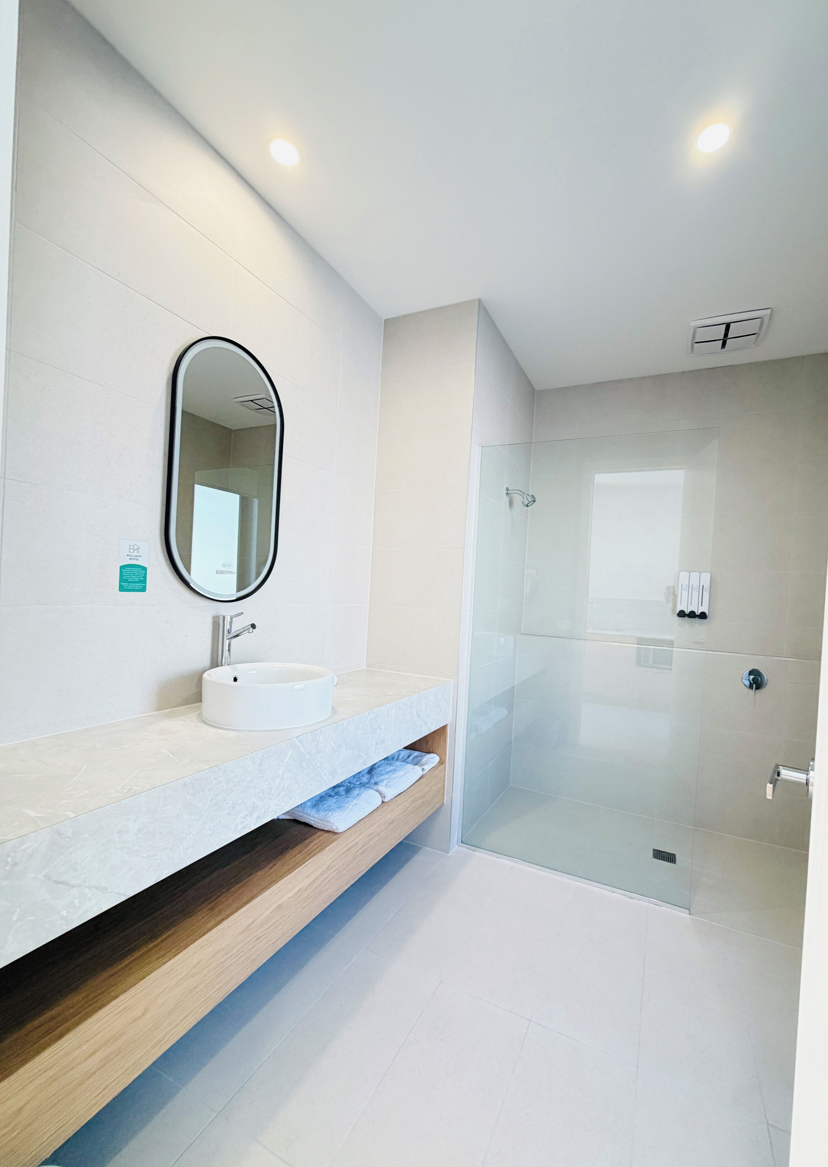 Un baño moderno con un lavabo blanco, un espejo y una ducha con mampara de vidrio.