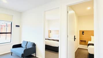 A hotel room with a sofa, a bed, and a small wooden cabinet.