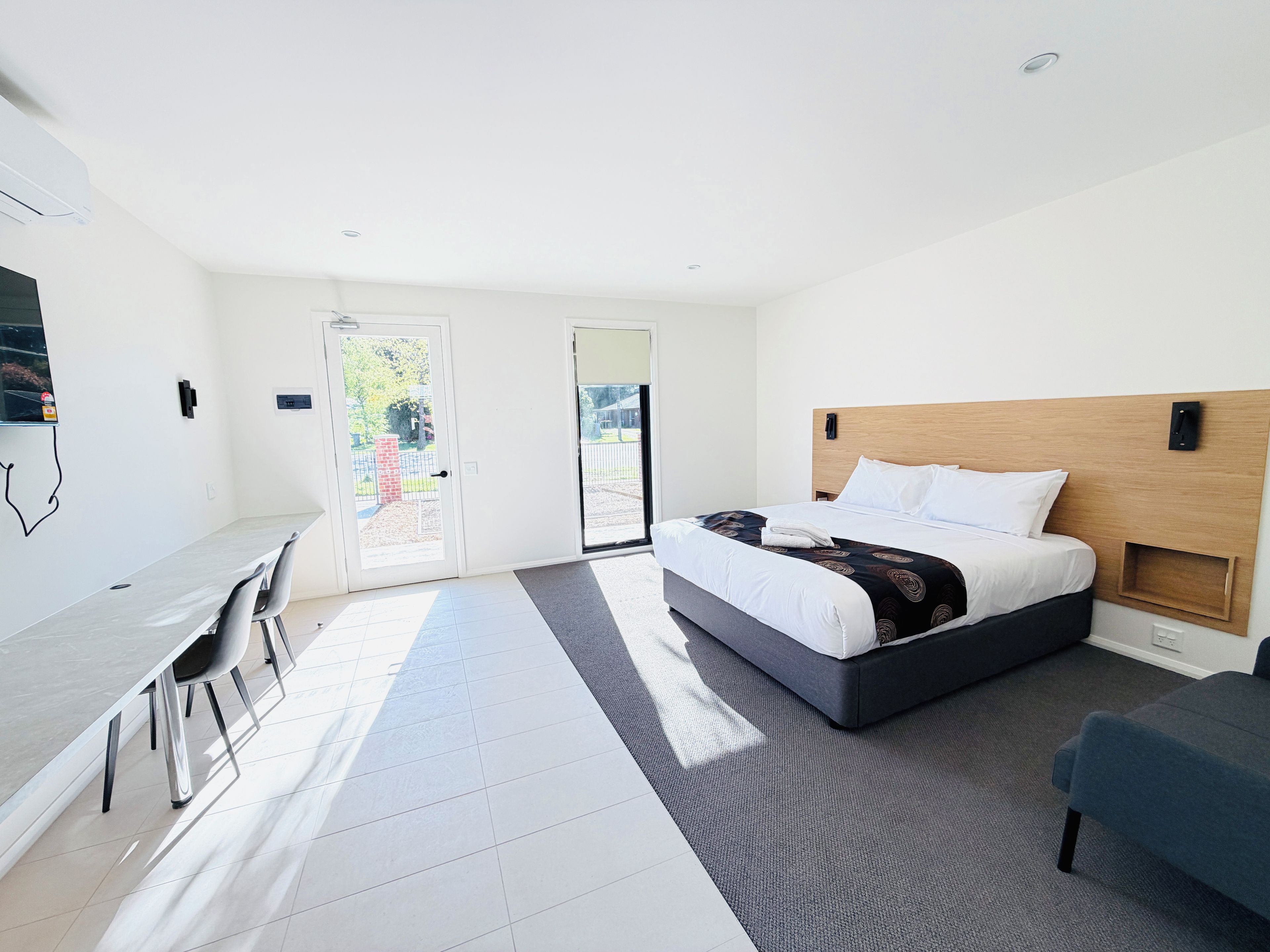 Et moderne hotelværelse med seng, skrivebord og stole.