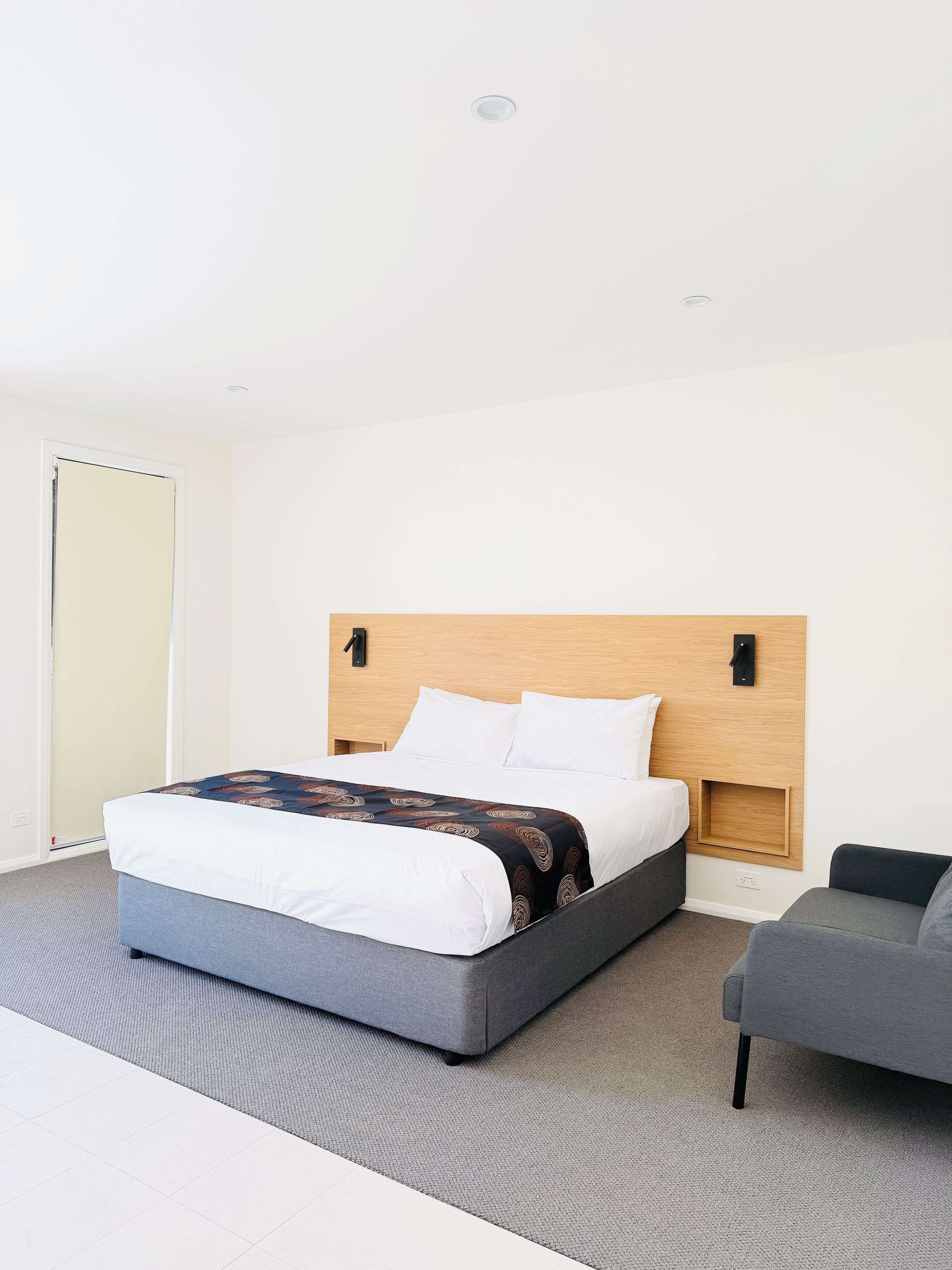 Una habitación de hotel con una cama, una mesita de noche, una silla y un armario.