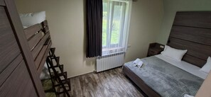 A bedroom with a bed, a nightstand, a wooden ladder, a window with curtains, and a radiator.