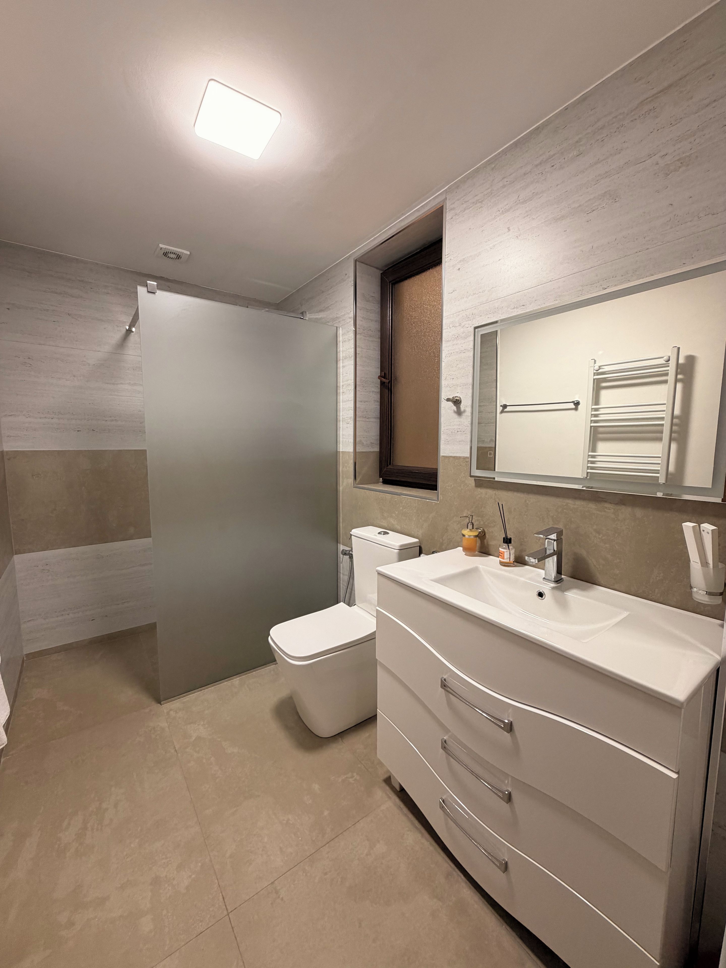 A modern bathroom with a toilet, sink, and mirror.