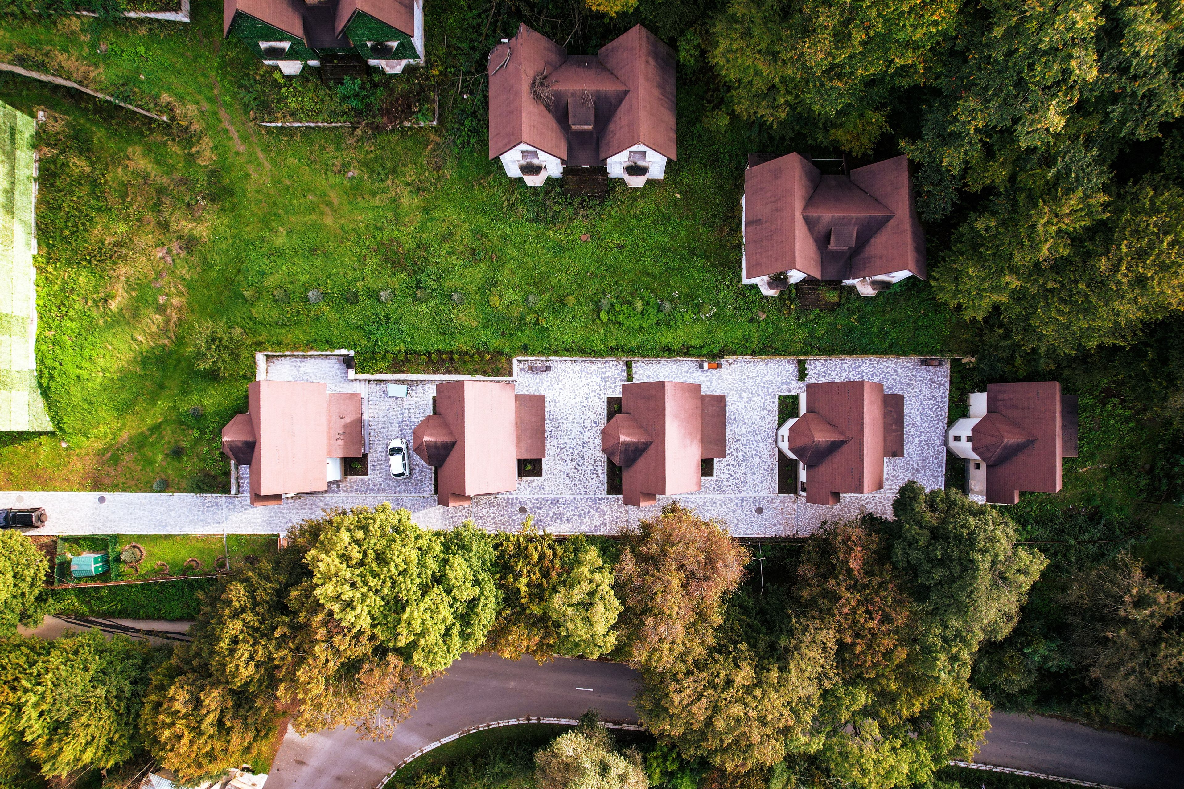 Vue aérienne d’une propriété comprenant plusieurs bâtiments, une allée pavée et de la végétation environnante.