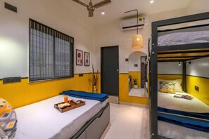 A hotel room with a bunk bed, a bedside table with a tray of snacks, a window with blinds, and an air conditioning unit. - Coliwo Un Hostel - Viman Nagar (Pune)