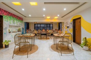 A dining area with two tables, chairs, and a mural on the wall. - Coliwo Un Hostel - Viman Nagar (Pune)