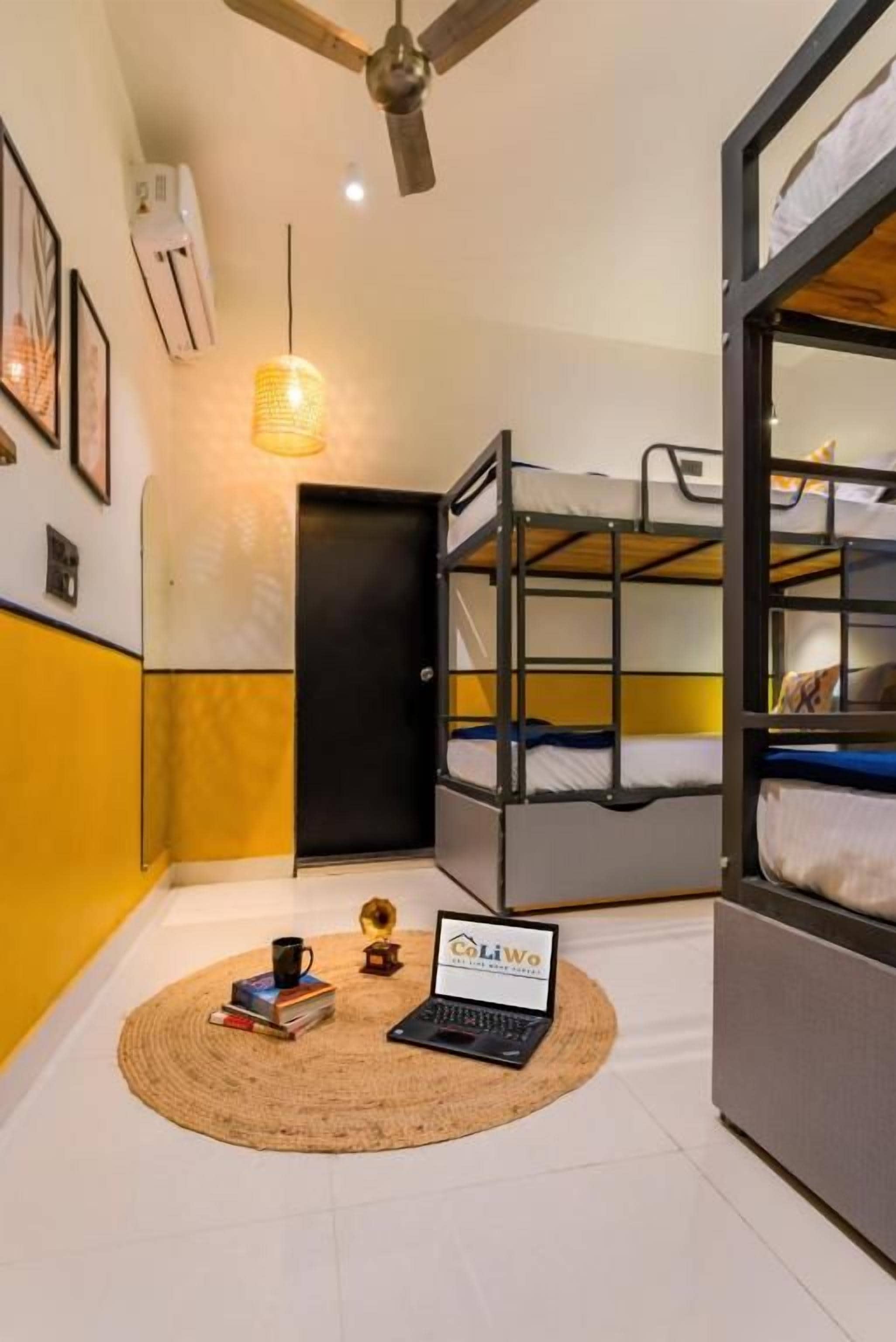 A room with bunk beds, a laptop, and a round rug.
