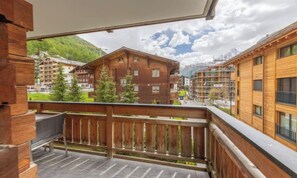 Un balcone in legno con vista su una montagna e degli edifici.