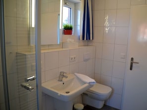 A bathroom with a sink, toilet, and a mirror. - Flurstrasse - OG Links (Wyk auf Foehr)