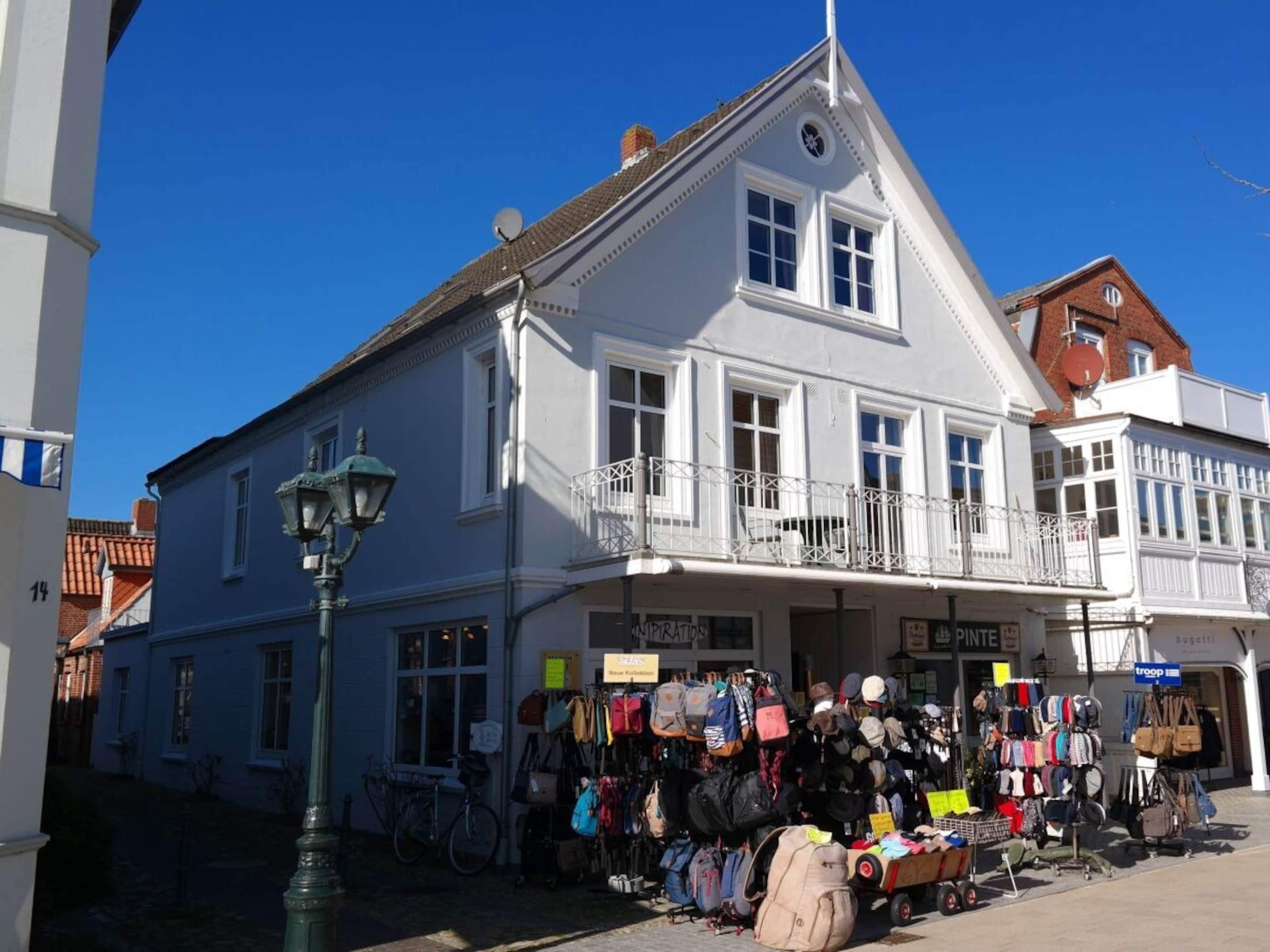 A building with a balcony and a shop selling bags and clothing.