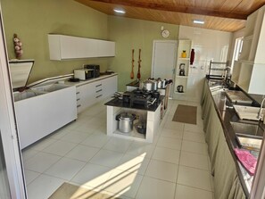 A kitchen with white cabinets, a stove, and a sink. - Beachfront, 10-suite house in Caponga, Ceara (Cascavel)