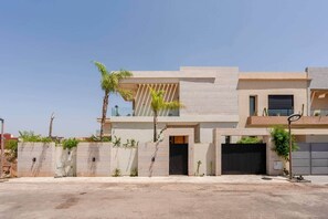 Una casa moderna de dos pisos amb teulada plana, un balcó i un garatge.