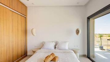 A modern bedroom with a large bed, a wooden wardrobe, and a view of the desert through a large window.