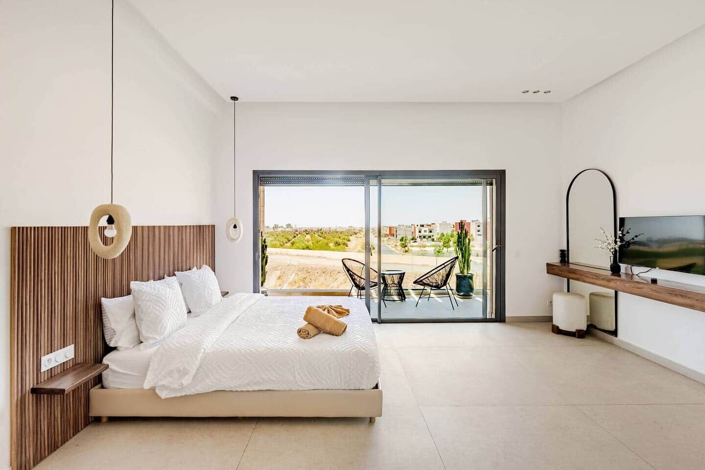 Una camera da letto con un letto, una TV, un balcone con sedie e vista sull'esterno.