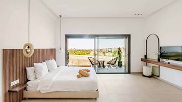 Una camera da letto con un letto, una TV, un balcone con sedie e vista sull'esterno.