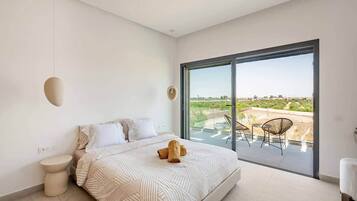 Une chambre moderne avec un grand lit, une vue sur l’extérieur et un balcon équipé de chaises.