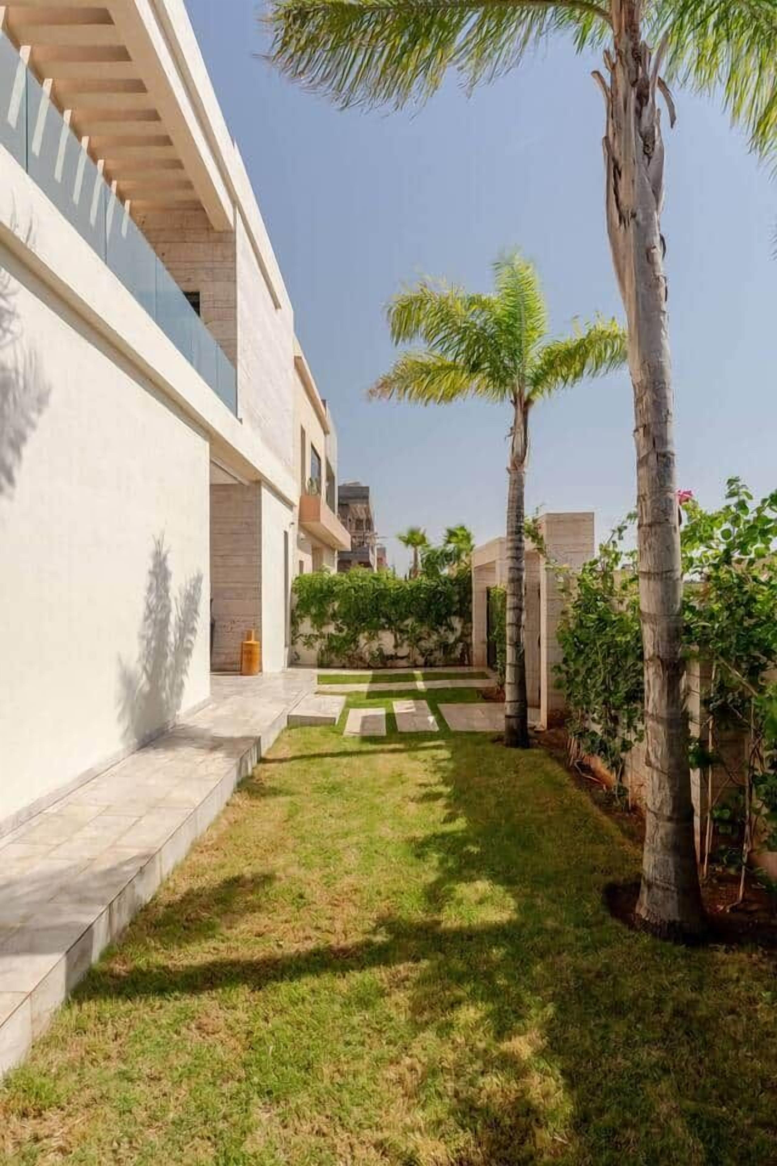 A modern building with a courtyard, palm trees, and a clear sky.
