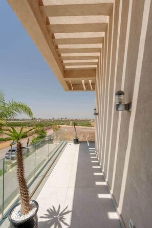 Un balcone con una vista aperta sul paesaggio, un cactus in vaso e una ringhiera in vetro.