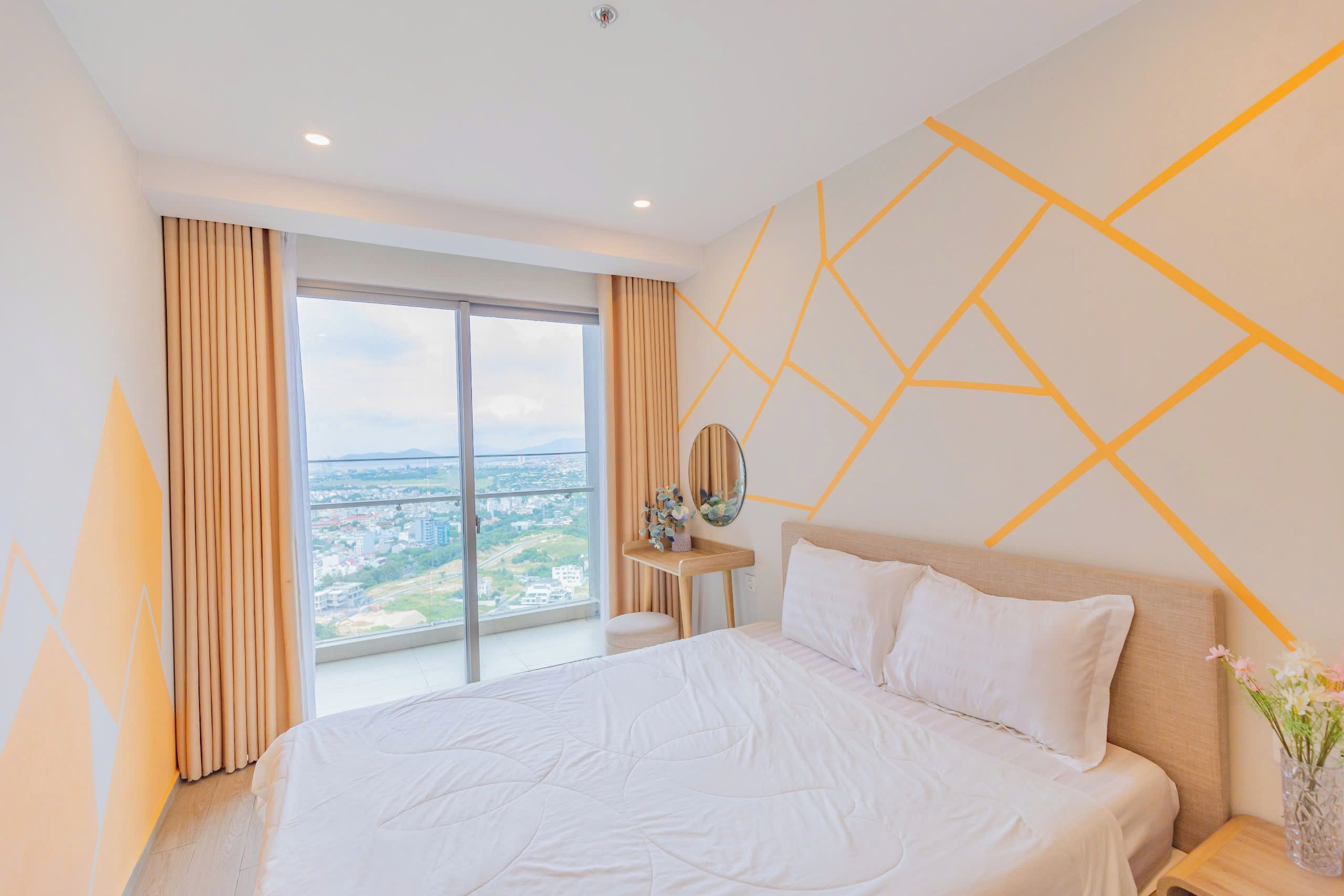 Une chambre d’hôtel moderne avec un grand lit, une vue sur le paysage urbain et un motif géométrique sur le mur.