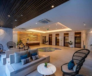 A modern lobby with a reception desk, seating area with sofas and chairs, and a marble floor. - The Song Retreat Apartment-Infinity Pool (Vung Tau)