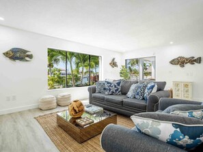 A modern living room with a grey sofa, ottomans, and a coffee table with decorative items. - SOMBRERO BEACH HOUSE WITH PRIVATE POOL AND DOCK (Marathon)