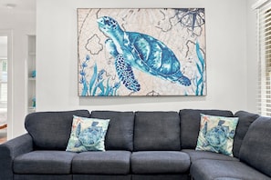 A living room with a grey sofa and two decorative pillows featuring a sea turtle design. - Sea Breeze 3-Unit Beach House 1 Block to Beach (North Myrtle Beach)