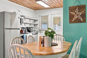 A modern kitchen with white appliances, a wooden ceiling, and a dining area with a wooden table and chairs. - Sea Breeze 3-Unit Beach House 1 Block to Beach (North Myrtle Beach)