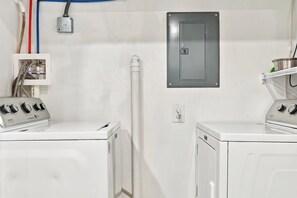 A laundry room with two washing machines, a utility meter, and a metal cabinet on the wall. - Sea Turtle at Sea Breeze Dog Friendly (North Myrtle Beach)