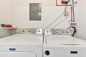 A laundry room with two Maytag washing machines, a metal utility panel, and a red and blue pipe system. - Sea Star One Block to the Beach Top Location (North Myrtle Beach)