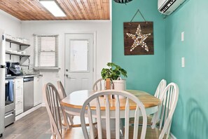 A dining area with a round table and white chairs, a potted plant, and a starfish decoration on the teal wall. - Sea Star One Block to the Beach Top Location (North Myrtle Beach)