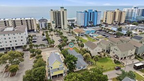 An aerial view of a coastal residential area with multiple-story buildings, a parking lot, and a clear view of the ocean. - Sea Star One Block to the Beach Top Location (North Myrtle Beach)