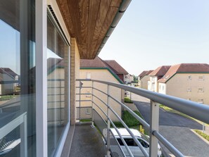 Ein Wohngebäude mit Balkon, einem geneigten Holzdach und Blick auf Nachbarhäuser.