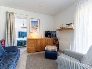 Ein modernes Wohnzimmer mit Sofa, Hocker, Fernseher, Holzschrank und Kamin.