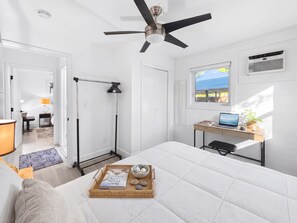 A modern bedroom with a bed, a desk, a ceiling fan, and a window with a view. - 2BR Home with BBQ Near Wynwood & Design District (Miami)