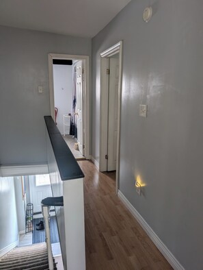 Ein Flur mit Holzboden, einer weißen Tür und einem Lichtschalter an der Wand.