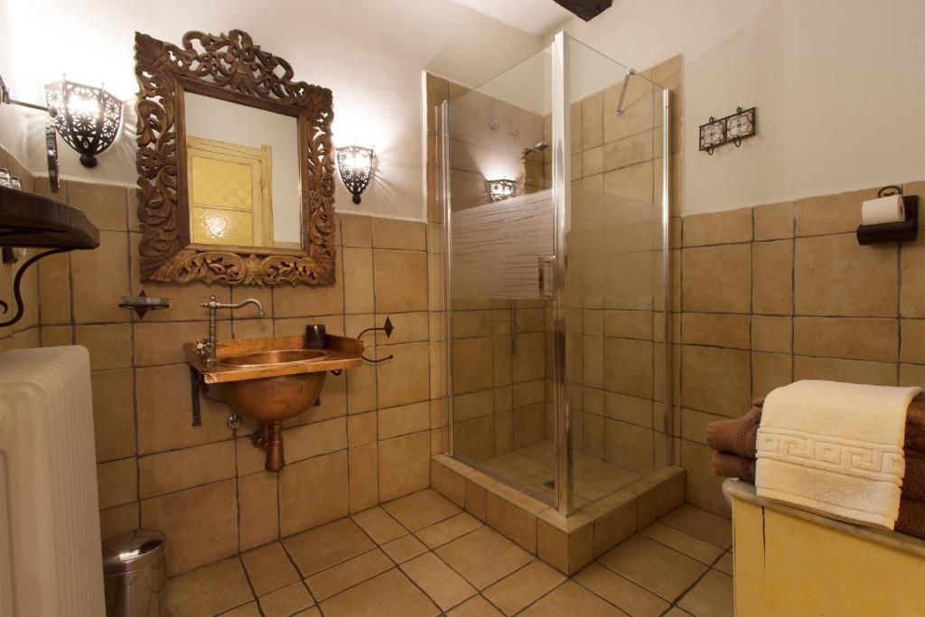 Une salle de bain avec un lavabo en cuivre, une douche à parois de verre, un miroir décoratif et un porte-serviettes.