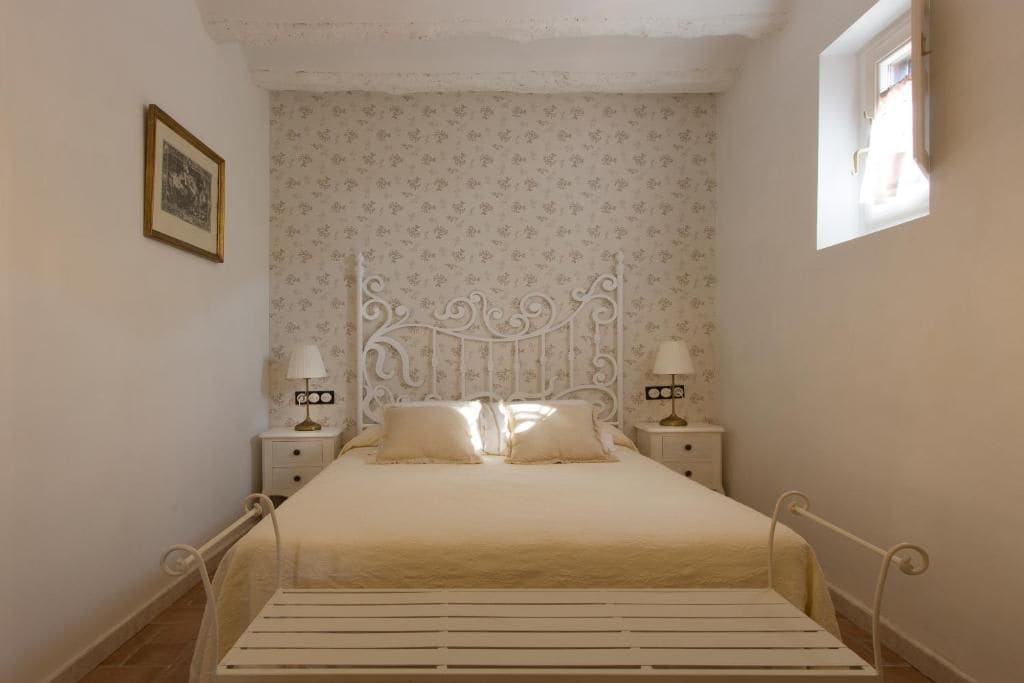 Een slaapkamer met een enkel bed, twee nachtkastjes en een raam.