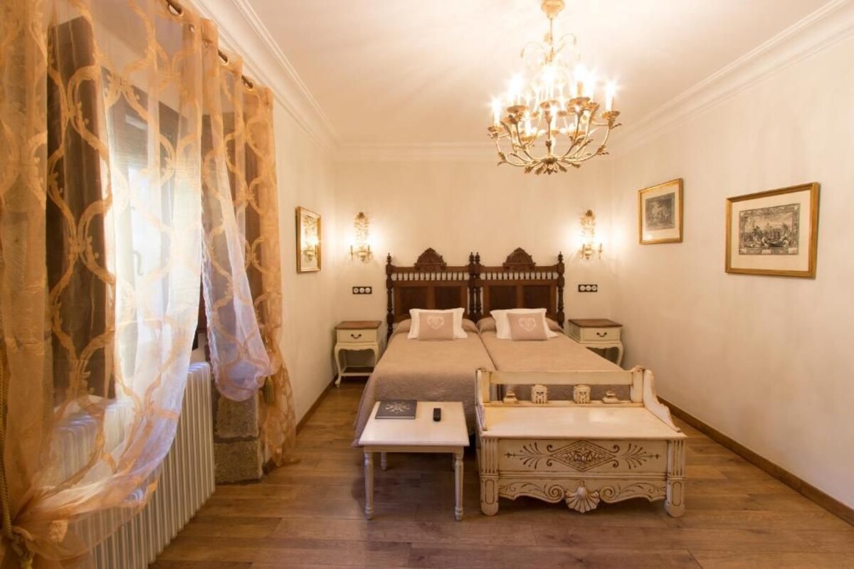 Una camera da letto con un letto matrimoniale, comodini, un lampadario e quadri appesi al muro.