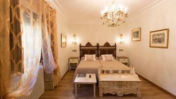 A bedroom with a double bed, bedside tables, a chandelier, and framed pictures on the wall.