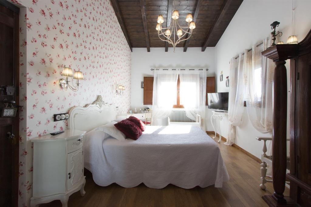 Un dormitorio con cama, mesita de noche, lámpara y televisor.
