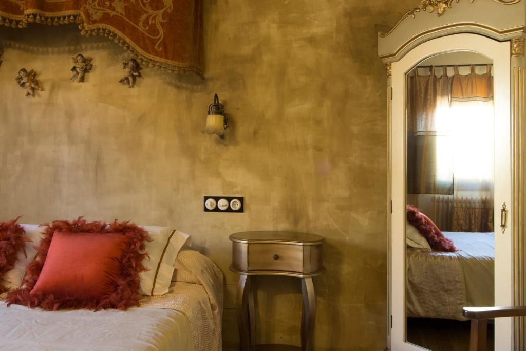 Une chambre à coucher avec un lit, une table de chevet, une horloge murale et un miroir.