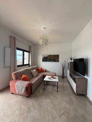 A modern living room with a sofa, a coffee table, a TV, and a ceiling light. - Villa la Hoya: Private Heated Pool and Sunsets (La Hoya)
