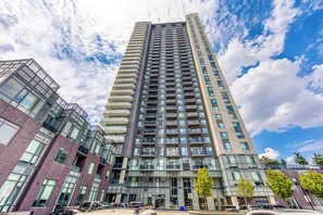 A high-rise building with multiple balconies, large windows, and a modern architectural design. - Fully furnished executive suite near Square One in the heart of Mississauga. (Mississauga)