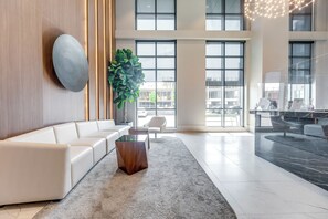 A modern lobby with a white sofa, a large plant, and a reception desk. - Fully furnished executive suite near Square One in the heart of Mississauga. (Mississauga)