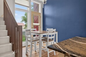 A dining area with a table and chairs, a wooden staircase, and a view through a glass door. - Rick's Chill Pad for 4 - Chic Downtown Billings Retreat (Billings)