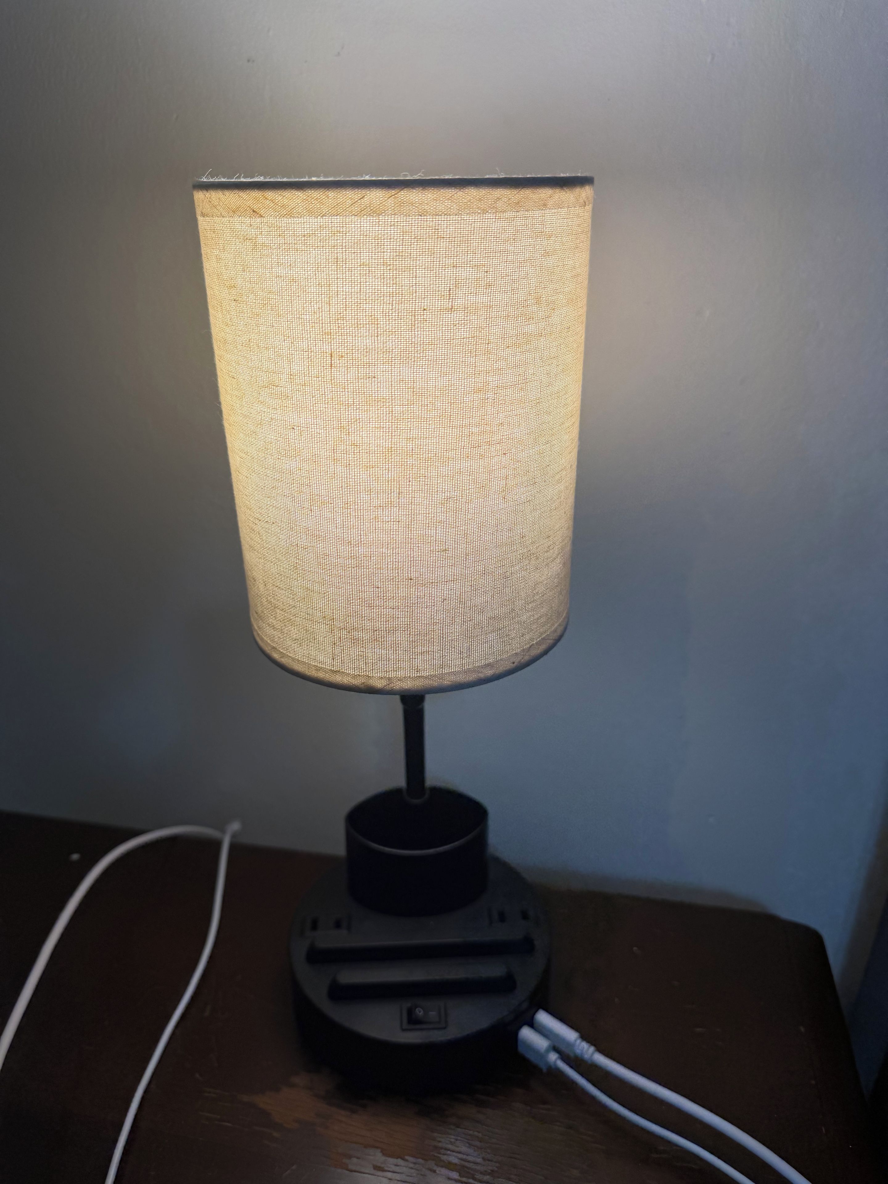A table lamp with a woven shade on a wooden surface.